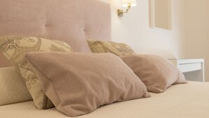 Un lit avec deux oreillers, une tête de lit et un luminaire fixé au mur.