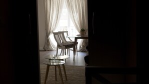 Une pièce avec une table en verre, deux chaises et une petite table sur laquelle se trouve une plante.