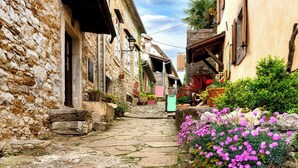 A narrow cobblestone street flanked by stone buildings with wooden shutters and potted plants. - Holiday apartment with Interntet access (Rabac)