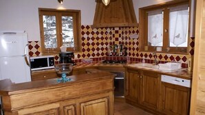 Eine Küche mit Holzausstattung, einer Mikrowelle, einer Kaffeemaschine und einer gefliesten Spritzschutzwand.