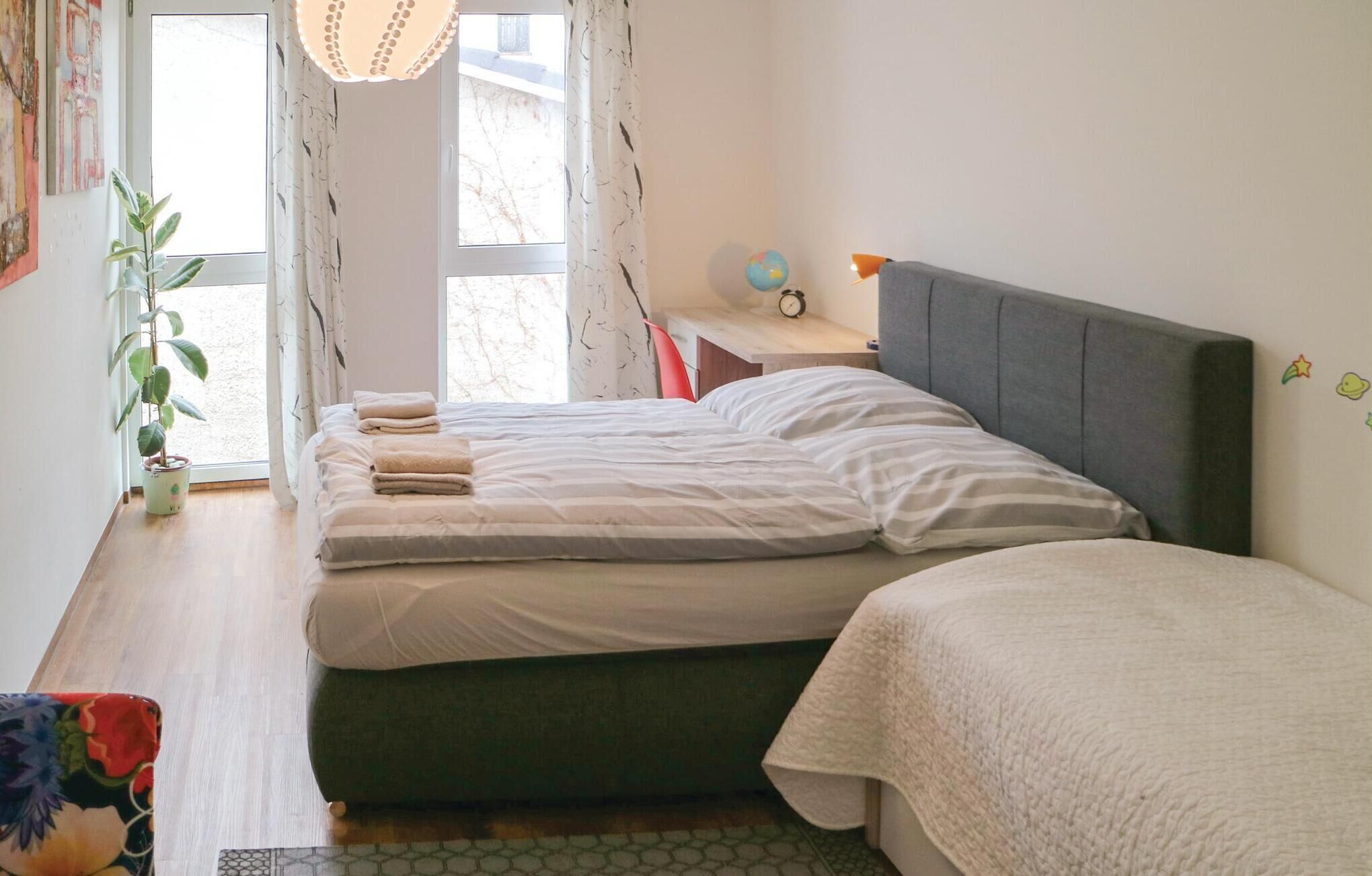 Une chambre à coucher avec un lit, une table de chevet, une lampe et une plante en pot.