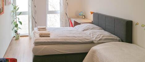 Une chambre à coucher avec un lit, une table de chevet, une lampe et une plante en pot.