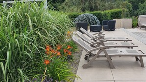 Patio esterno con poltrone relax e un ombrellone decorativo.
