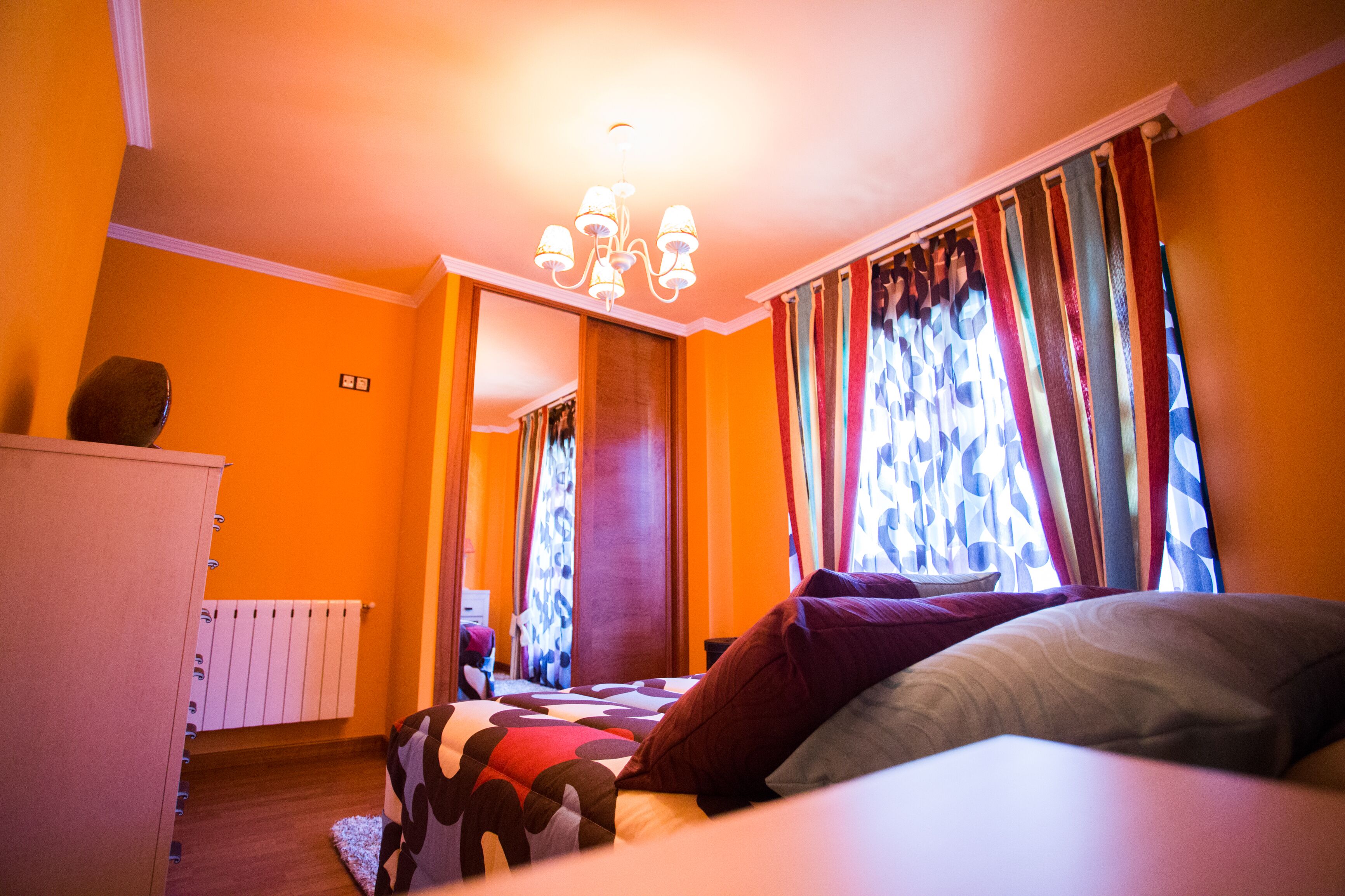 Un dormitorio con una cama, un radiador y cortinas.