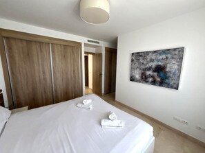 A hotel room with a bed, a wardrobe, a painting, and a hallway.