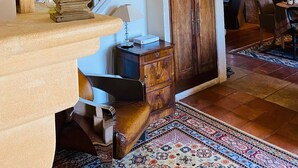 Een trap met een geweven hoed op de leuning, een houten kast en een kamerbreed tapijt.