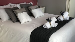 A neatly made bed with white and grey pillows, a black throw blanket, and rolled towels with lavender. - Discover Sitges, steps from the beach. 3 BRM + 2 BATH (Sitges)