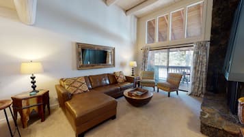 A cozy living room with a brown leather sofa, two armchairs, a coffee table, and a fireplace.