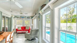 Une pièce lumineuse, baignée de soleil, avec une piscine, un ventilateur de plafond et un coin repas.
