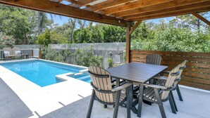 Un espace extérieur abrité comprenant une piscine, une terrasse en bois et des sièges.