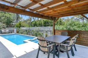 A covered outdoor area with a pool, wooden deck, and seating.