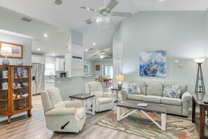 Un salon spacieux comprenant un canapé, des fauteuils, une table basse et, au fond, un coin repas.