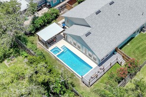 A residential property with a swimming pool, a covered patio, and a fenced yard.