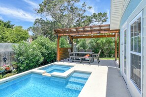 Ein Garten mit Schwimmbad, einer Holz-Pergola und einem Esstisch mit Stühlen.