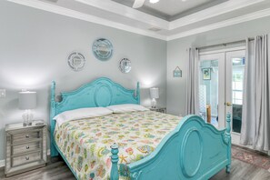 A bedroom with a bed, bedside tables, and a door with curtains.