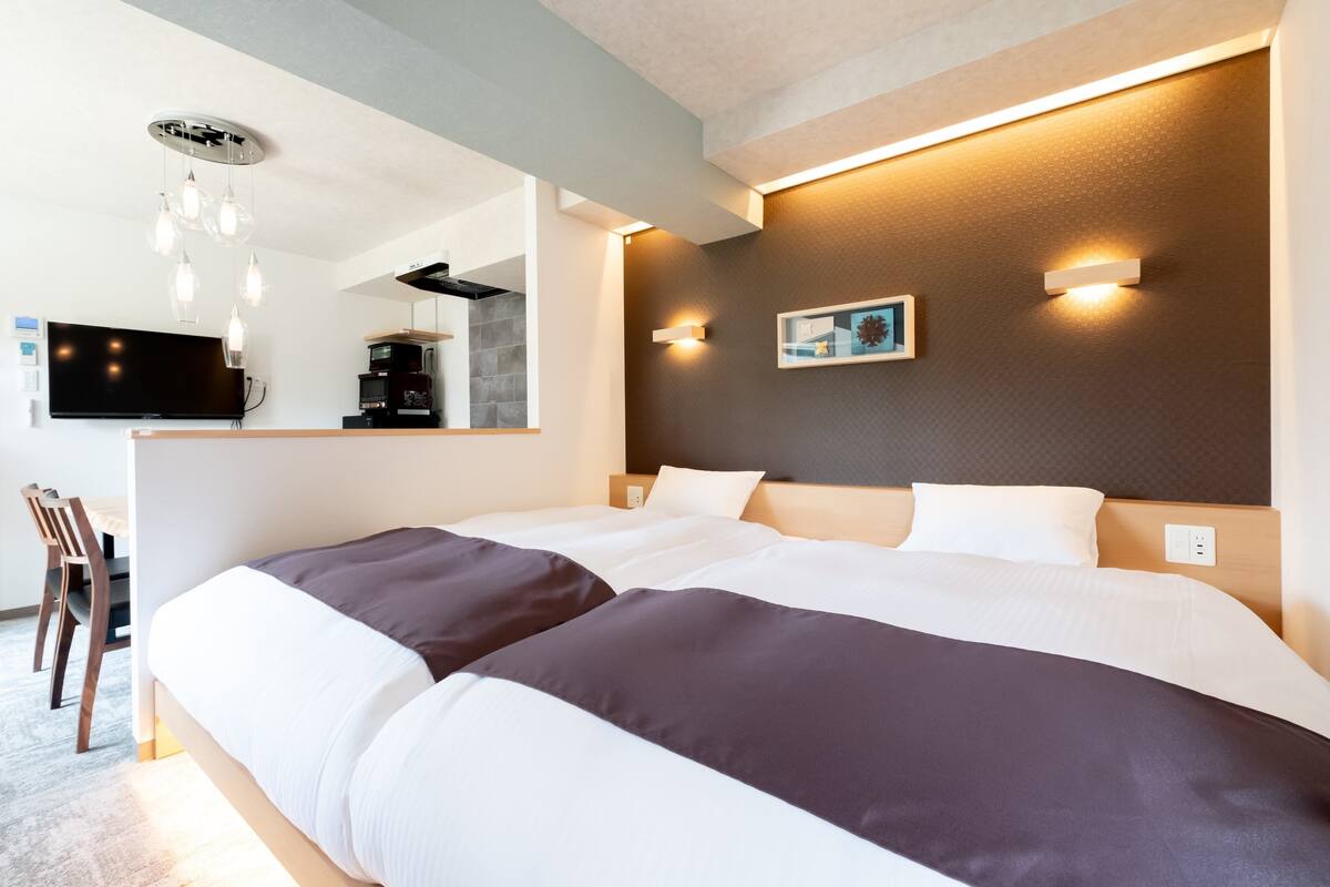 A modern hotel room with a large bed, a desk, and a television.