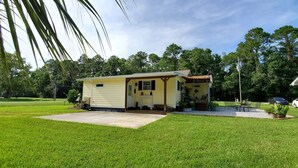 Une petite maison de plain-pied avec un porche à l’avant, un garage et une pelouse bien entretenue.