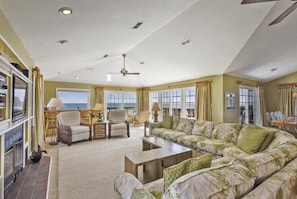 A spacious living room with a large sofa, armchairs, a coffee table, and a television. - The Lawrence at Ships Watch in Duck Fabulous Ocean Front Home (Duck)