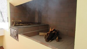 A brick fireplace with burning wood, a metal firebox, and a chimney emitting smoke.