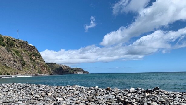 A rocky beach with a clear sky and distant hills.