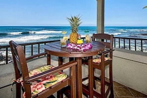 Enjoy a seaside view from this balcony with a table and chairs, perfect for a relaxing moment.