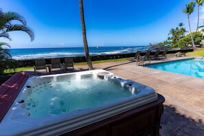 Relax by the pool with a hot tub and lounge chairs, surrounded by palm trees and a beautiful ocean view.