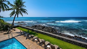 Un espace aménagé au bord de la piscine, avec des chaises longues et une vue sur l’océan.