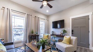Un salon comprenant un canapé, un fauteuil, une table basse et un téléviseur fixé au mur.
