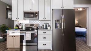 Une cuisine moderne avec des meubles blancs, des appareils en acier inoxydable et un four à micro-ondes encastré.