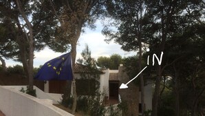 A building with a stone facade, a flag, and a pathway. - You cook, eat and relax around the pool with nice sea view. (Palafrugell)