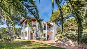 A two-story house with a balcony, surrounded by lush greenery and a stone wall. - You cook, eat and relax around the pool with nice sea view. (Palafrugell)