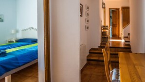 A room with a bed, a wooden table, and a staircase leading to another area. - You cook, eat and relax around the pool with nice sea view. (Palafrugell)