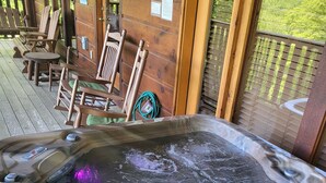 Un bain à remous avec une terrasse en bois, des chaises et une vue sur le paysage.