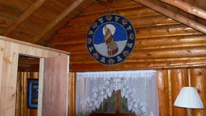 En interiör med träpanel och en cirkelformad symbolmärkning i taket, ett fönster dekorerat med spets och en trädörr.