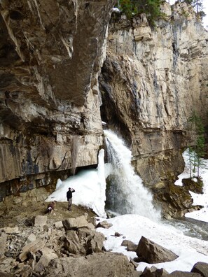 A waterfall cascading down a rocky cliff with a person standing in the foreground.