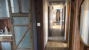 A hallway with wooden flooring, a metal door, and a wooden wall with a horn decoration. - HaT Ranch Lodge. Perfect for a large group or multiple families. NO CLEANING FEE (Ponca City)