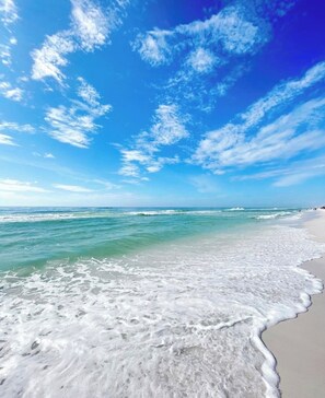 Une plage avec une eau d’un bleu limpide et un rivage sablonneux.