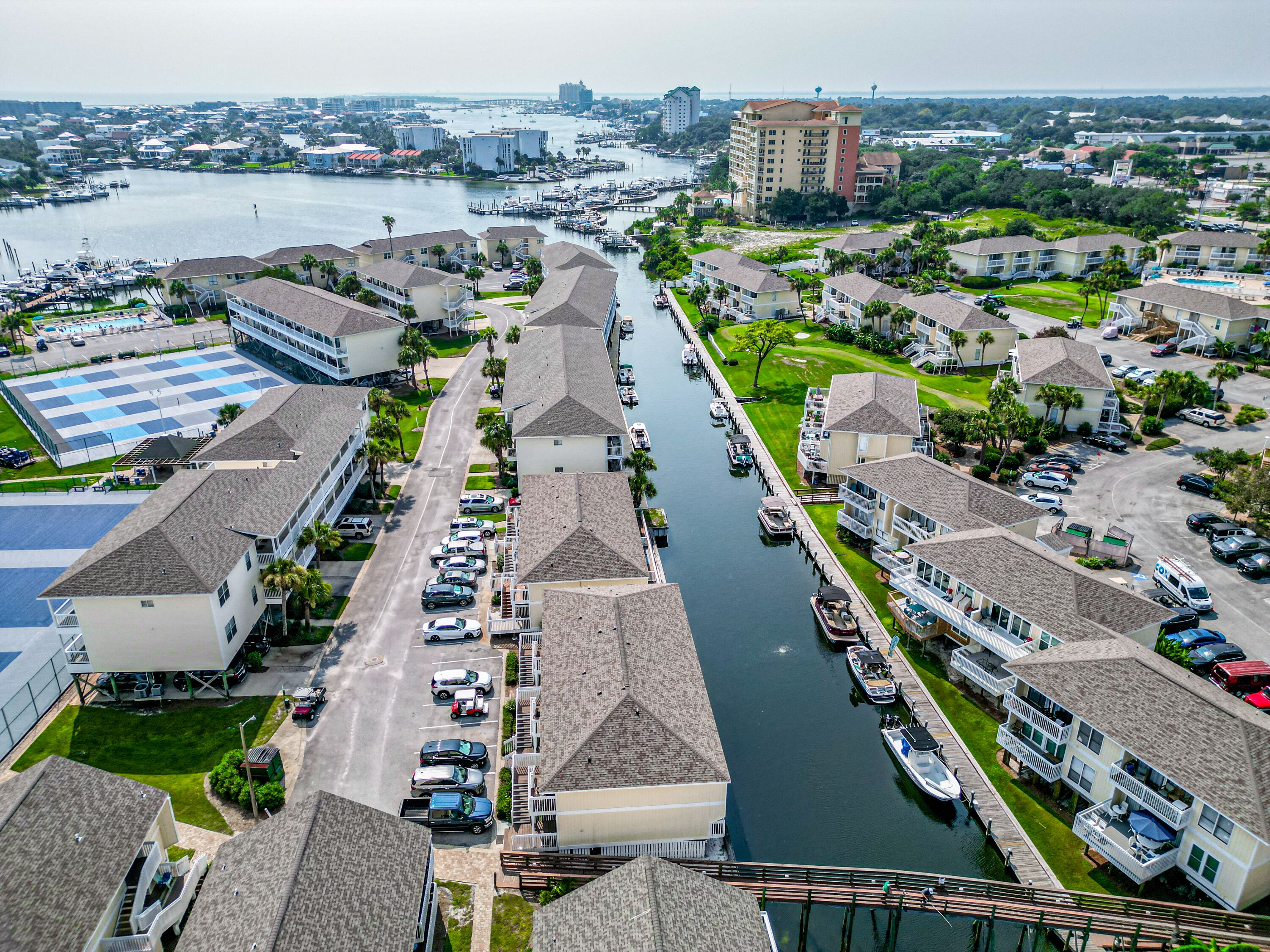 A marina with boats docked, a waterway between buildings, and a view of the city skyline in the distance.