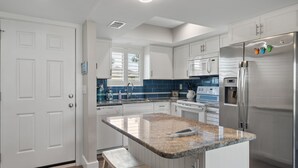 Una cocina moderna con armarios blancos, encimera de granito y electrodomésticos de acero inoxidable.
