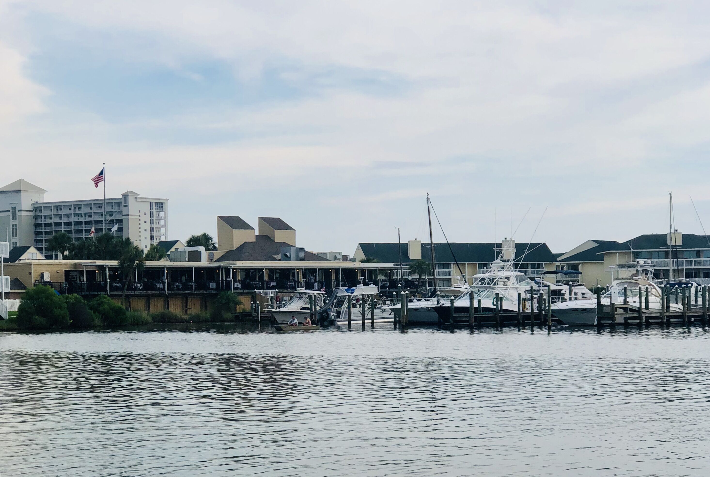 A marina with docked boats, a flag, and buildings in the background.