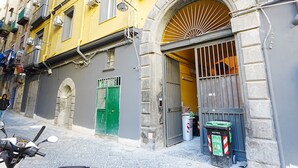 A narrow street with a yellow building, a green door, and a parked scooter. - Apartment in the heart of the Spanish Quarter, next to Via Toledo. (Napoli)