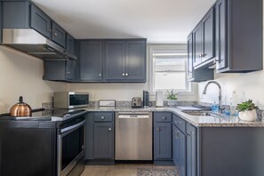 A modern kitchen with dark cabinets, stainless steel appliances, and a granite countertop.