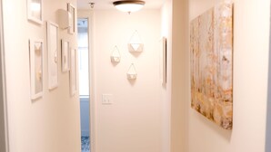 Een gang met een lamp, ingelijste foto's en een groot abstract schilderij aan de muur.