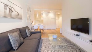 A modern living room with a sofa, a flat-screen TV, and a dining area with a table and chairs. - Viena | The Rentals Collection (San Sebastián)