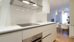 A modern kitchen with white cabinetry, a stainless steel range hood, and pendant lighting. - Viena | The Rentals Collection (San Sebastián)