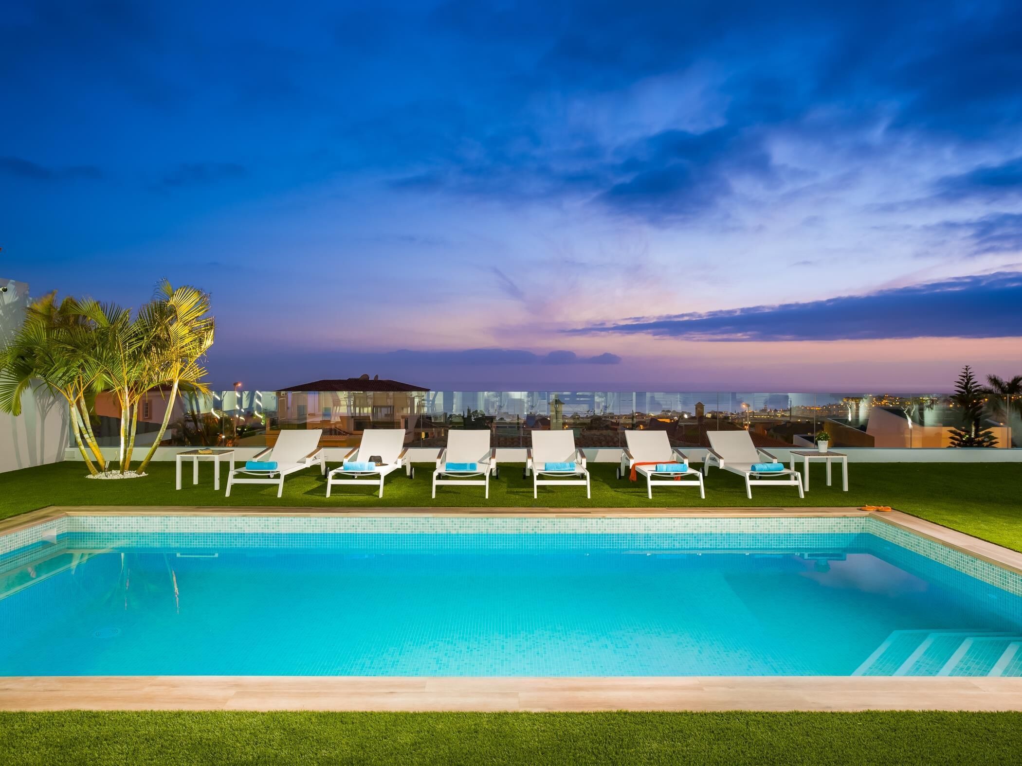 Una piscina con sillas de descanso y palmeras.