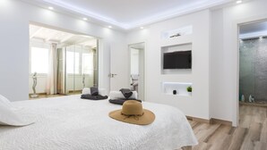 Una habitación de hotel moderna con una cama grande, televisión y zona de ducha.