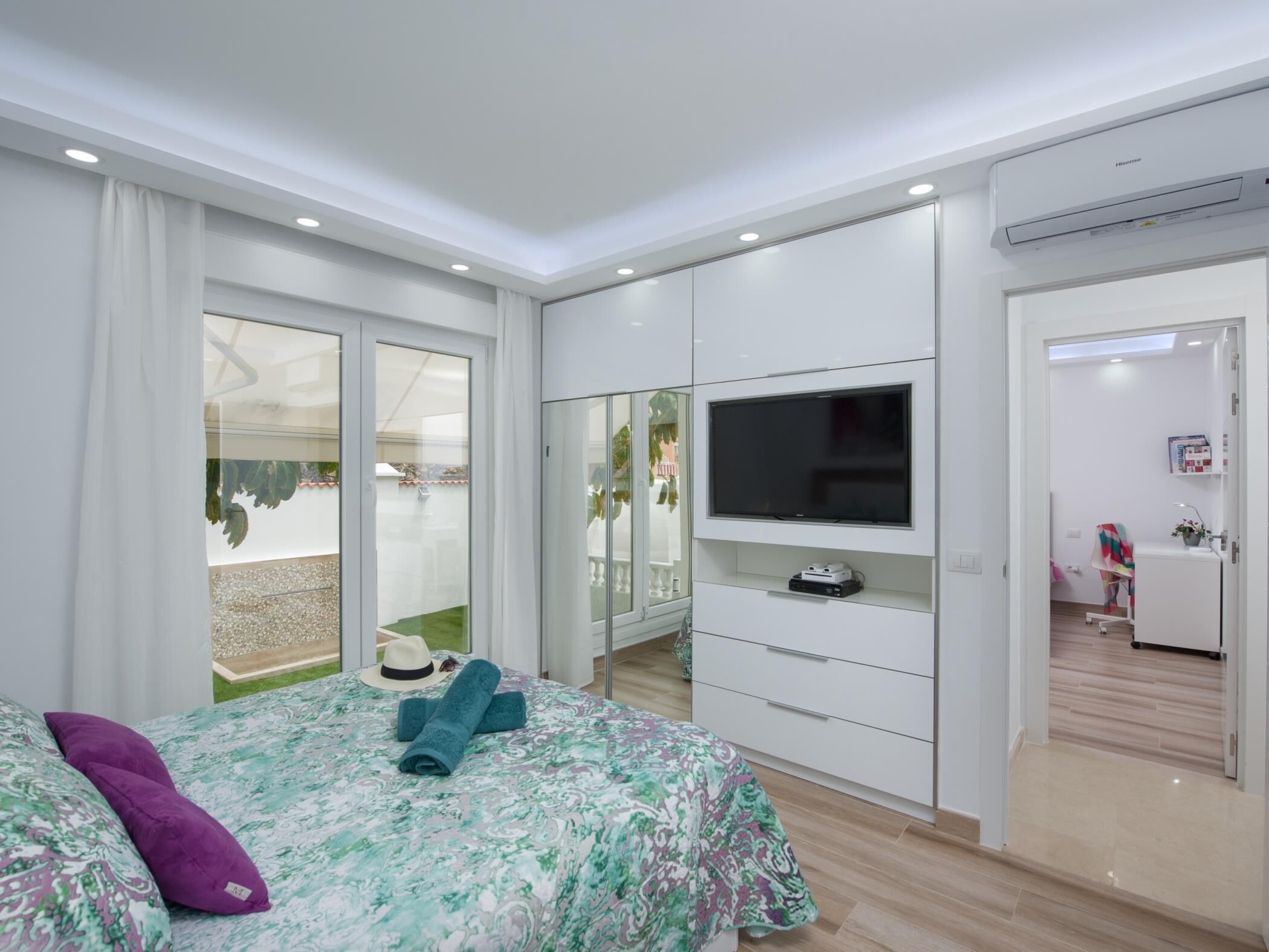 A modern bedroom with a bed, a TV, and a wardrobe.