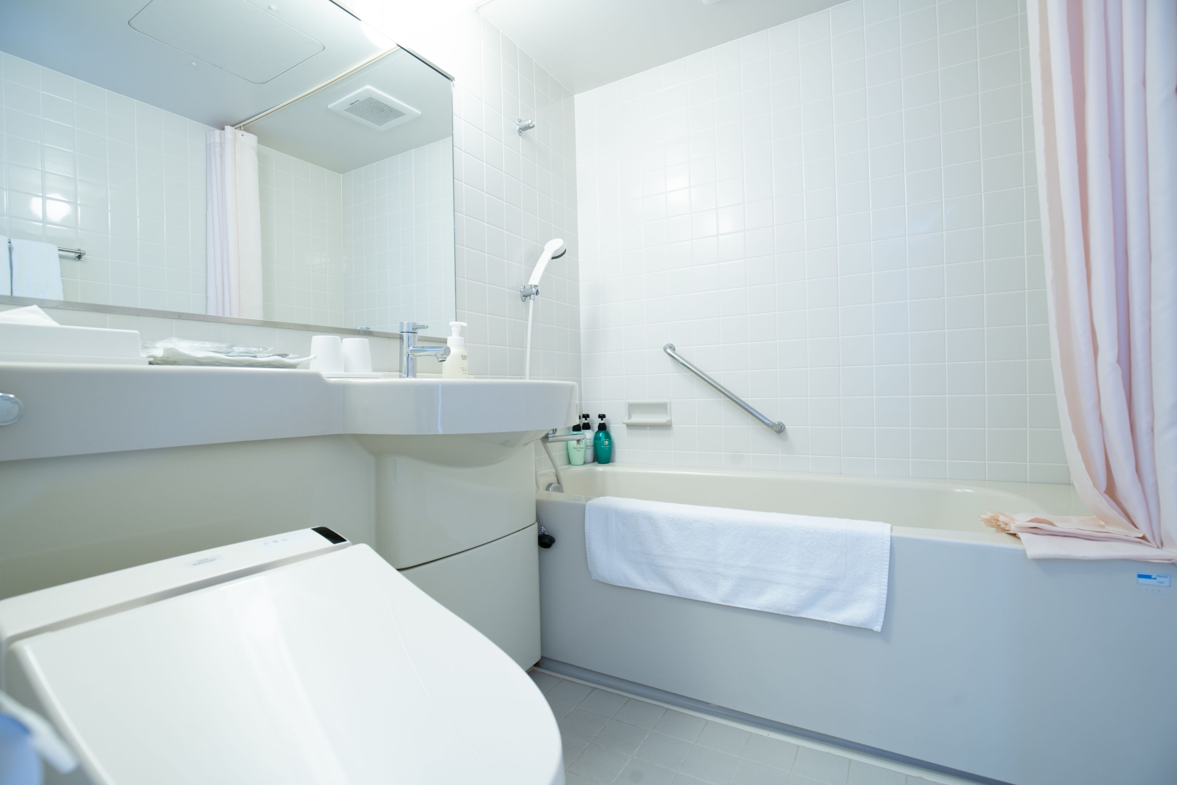 A modern bathroom with a sink, mirror, and bathtub.