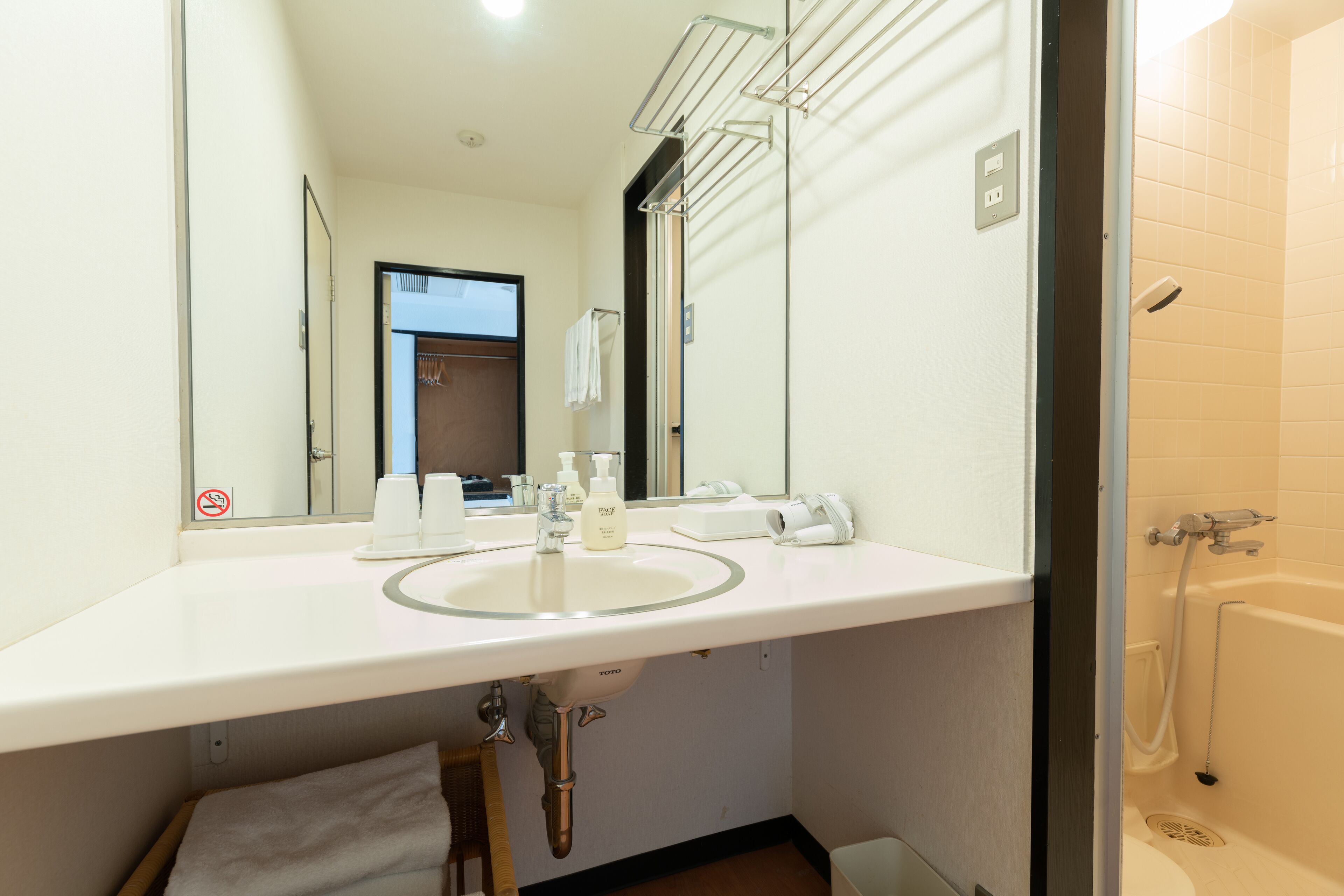 Un baño de hotel con un lavamanos blanco, un espejo y una ducha.